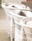 Row of white Malawi chairs placed at a dining table, styled with grey and white cushions in a modern rustic interior.